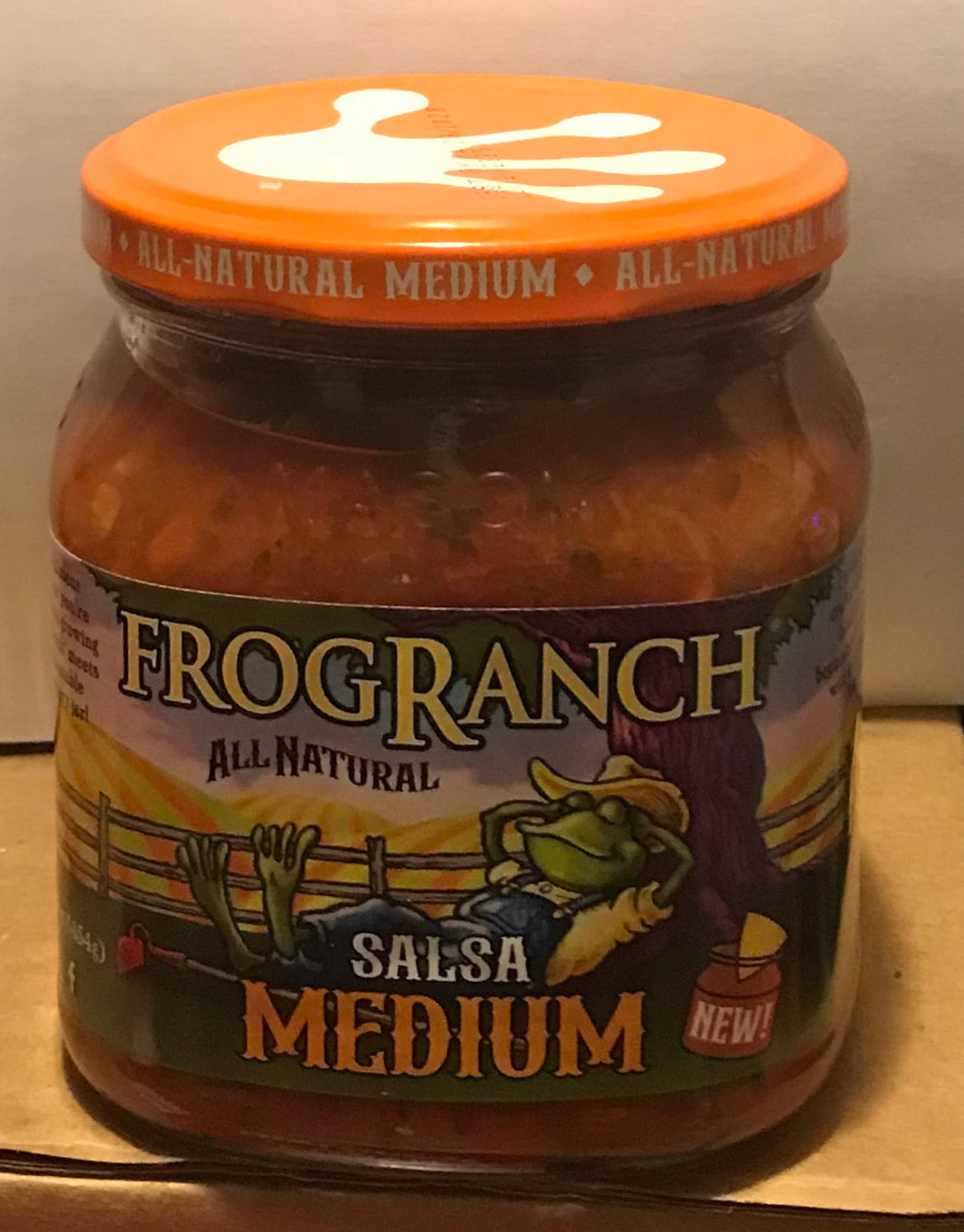 Jar of Frog Ranch Medium Salsa on a cardboard surface with a neutral background